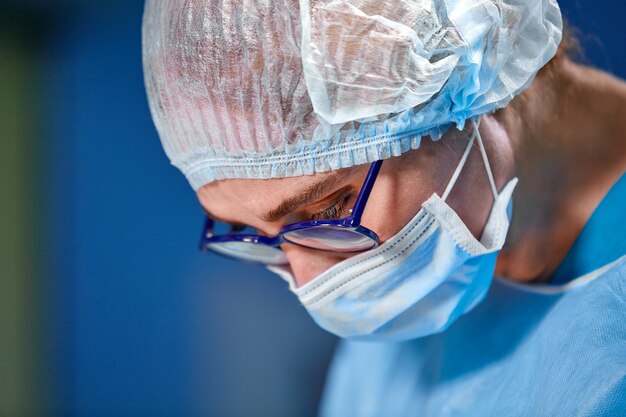 Chirurgo femminile in sala operatoria con la riflessione in bicchieri.