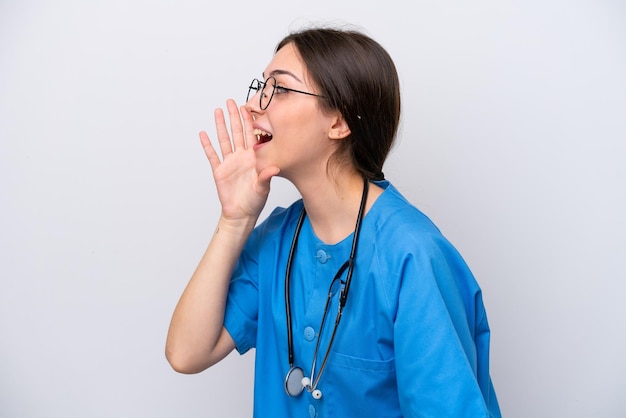 Chirurgo medico donna che tiene strumenti isolati su sfondo bianco che grida con la bocca spalancata sul lato