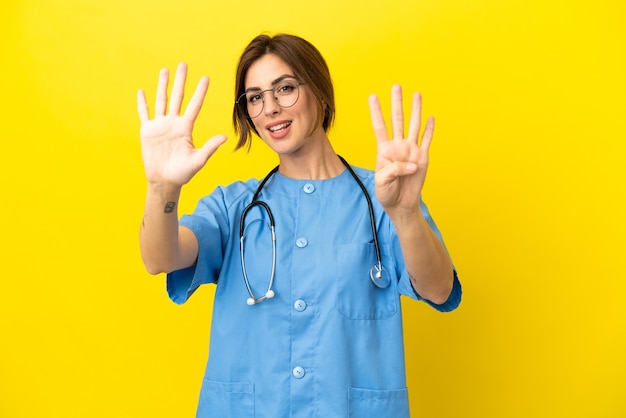 Chirurgo medico donna isolata su sfondo giallo contando nove con le dita