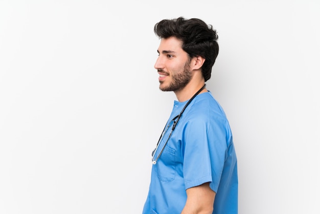 Chirurgo medico uomo sopra isolato muro bianco in piedi e guardando al lato