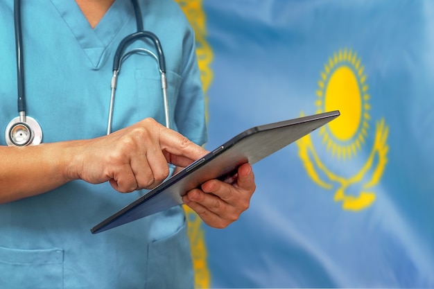 Chirurgo o medico utilizzando una tavoletta digitale sullo sfondo della bandiera del Kazakistan