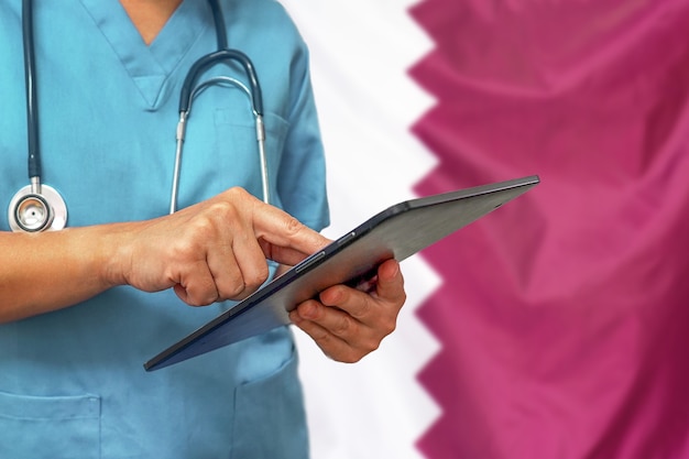 Chirurgo o medico utilizzando una tavoletta digitale sullo sfondo della bandiera del Qatar