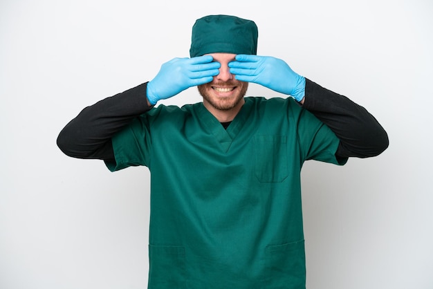 Chirurgo Uomo brasiliano in uniforme verde isolato su sfondo bianco che copre gli occhi con le mani