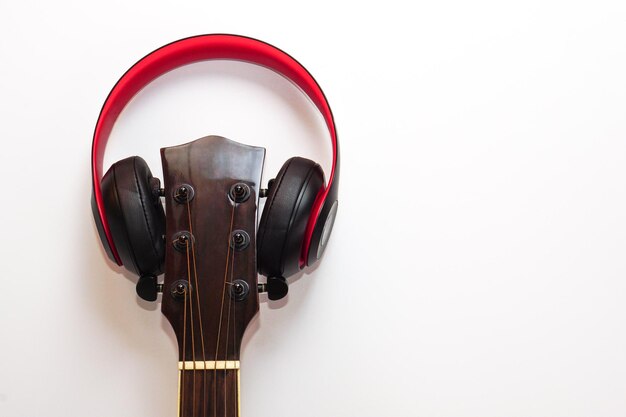 Chitarra acustica e le cuffie su sfondo bianco Concetto di svago, relax e musica