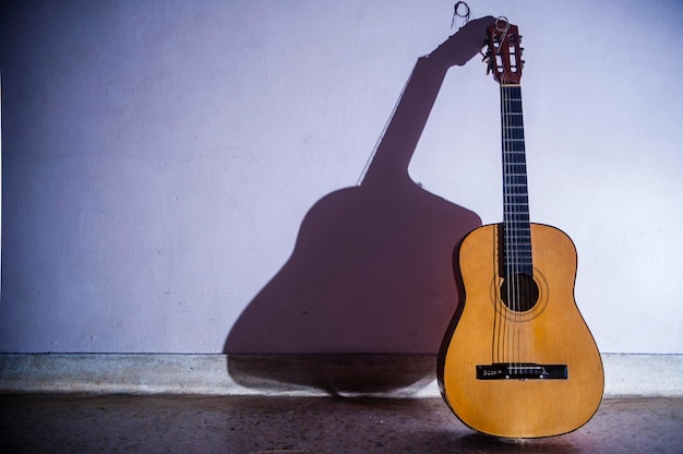 Chitarra acustica sul pavimento contro il muro a casa