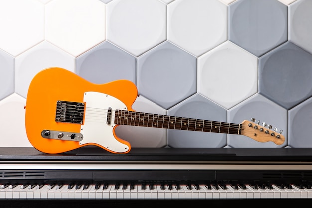 Chitarra elettrica arancione che pone sul piano. concetto per la scuola di musica