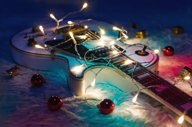 Chitarra elettrica con ghirlanda illuminata su sfondo scuro. Forme classiche per chitarra regalo per Natale o Capodanno.