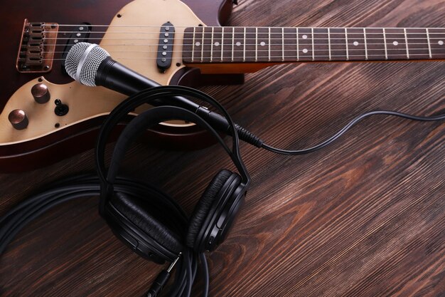 Chitarra elettrica con microfono e cuffie sul tavolo di legno da vicino