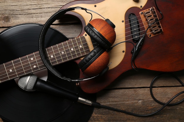 Chitarra elettrica e cuffie con microfono e vinile su sfondo di legno