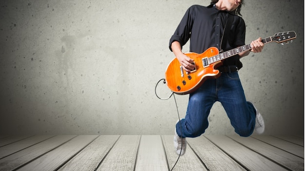 Chitarrista maschio che suona musica su sfondo grigio muro