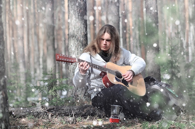 Chitarrista nel bosco a un picnic. Un musicista con una chitarra acustica in una tenda nella foresta. Riposare con una chitarra all'aperto all'aperto