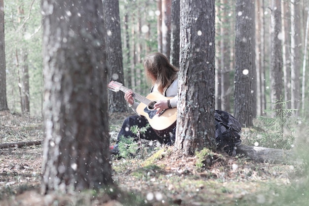 Chitarrista nel bosco a un picnic. Un musicista con una chitarra acustica in una tenda nella foresta. Riposare con una chitarra all'aperto all'aperto