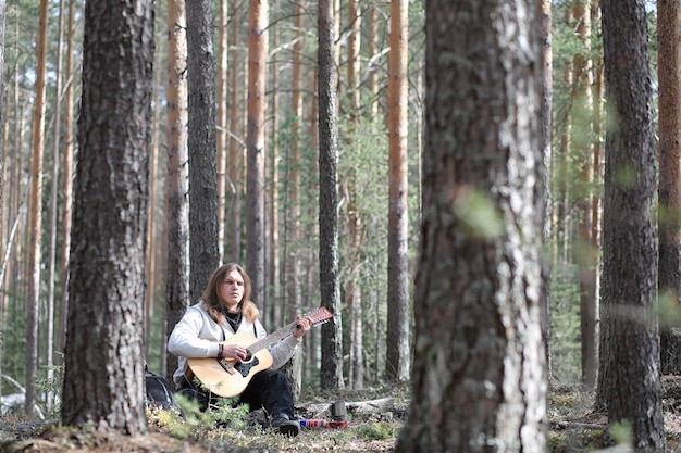 Chitarrista nel bosco a un picnic. Un musicista con una chitarra acustica in una tenda nella foresta. Riposare con una chitarra all'aperto all'aperto