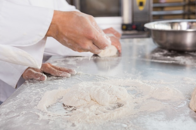 Chiuda in su dei panettieri che impastano la pasta al contatore