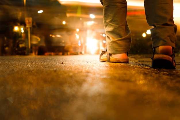 Chiuda in su dei sandali dell&#39;uomo che camminano nella notte della città.