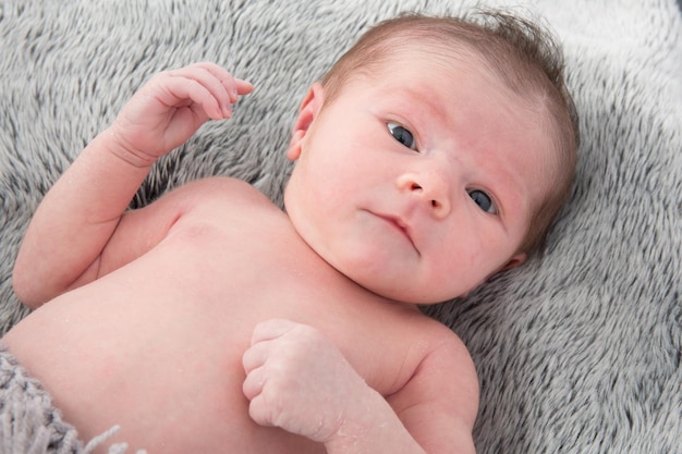 Chiuda in su del bambino appena nato sveglio che esamina la macchina fotografica