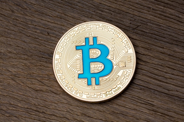 Chiuda in su del bitcoin blu dorato su fondo di legno