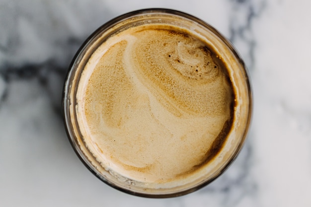 Chiuda in su del caffè Latte sporco con struttura in marmo sul caffè e sul tavolo.