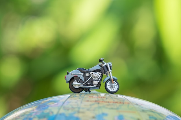 Chiuda in su del giocattolo miniatura del motociclo sulla mappa del pallone del mondo