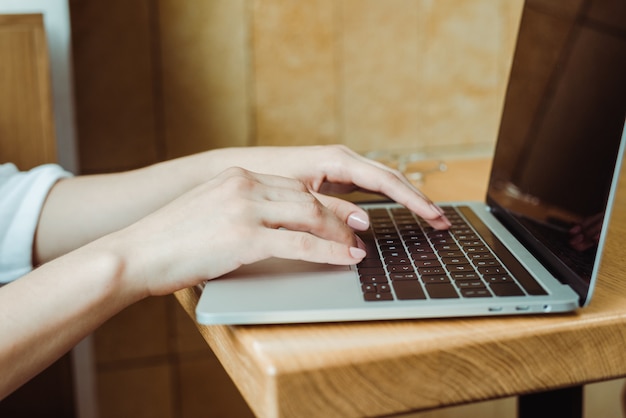 Chiuda in su del lavoro manuale della ragazza il laptop a casa