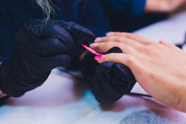 Chiuda in su del manicure trattato della Francia al salone di bellezza.