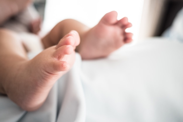 Chiuda in su del piede del bambino sulla coperta bianca