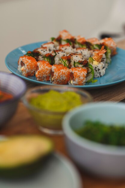 Chiuda in su del rotolo di sushi impostato su un piatto di ingredienti intorno alla natura morta