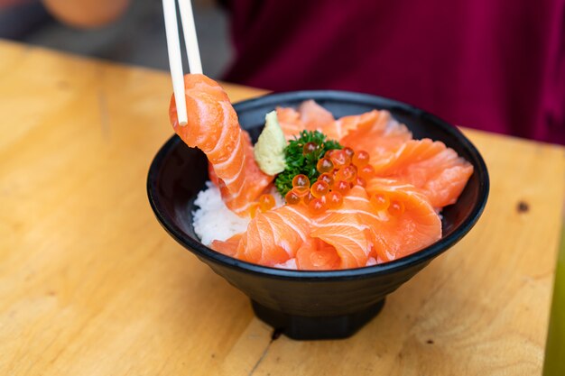 Chiuda in su del salmone don, sashimi fresco, salmone crudo, uova di salmone, wasabi sulla tavola di legno.