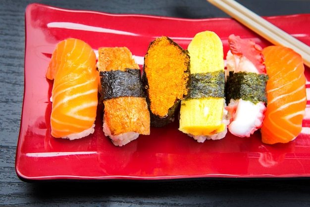 Chiuda in su del set di sushi sashimi servito sulla piastra rossa