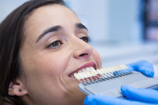 Chiuda in su dell'attrezzatura della holding del dentista mentre esamina la donna alla clinica