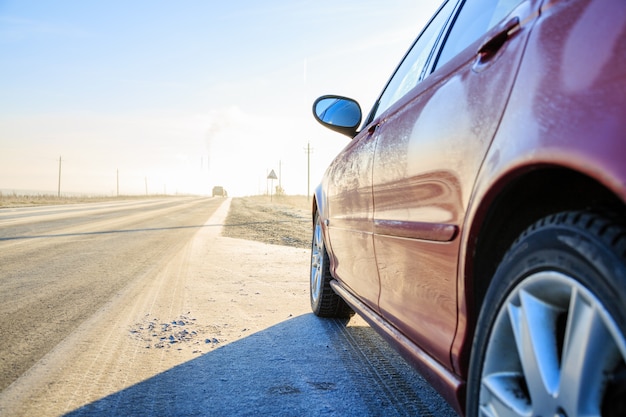 Chiuda in su dell'automobile sulla brina coperta strada