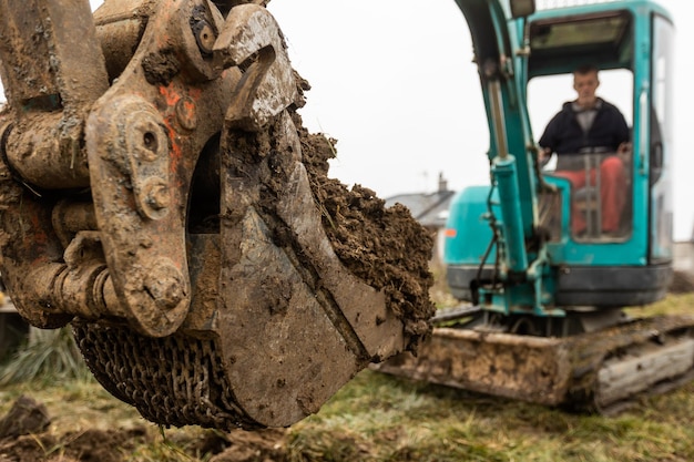 Chiuda in su dell'escavatore o della scavatrice che scava un certo concetto industriale del terreno o dell'argilla