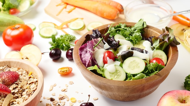 Chiuda in su dell&#39;insalata di verdure miste, muesli e frutta fresca su priorità bassa bianca.