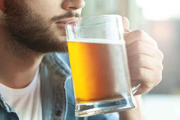 Chiuda in su dell'uomo barbuto che beve birra