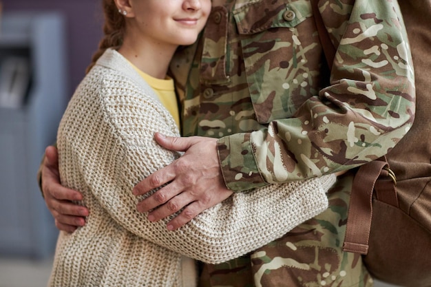 Chiuda in su dell'uomo che indossa l'uniforme militare che abbraccia la figlia