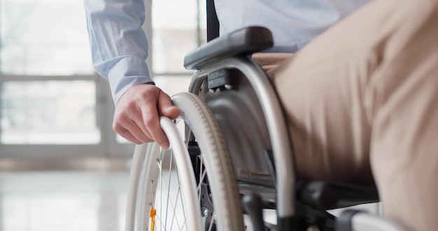 Chiuda in su dell'uomo disabile che guida in sedia a rotelle