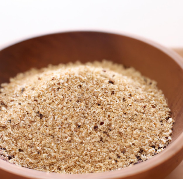 Chiuda in su della ciotola di più chicchi di riso quinoa su sfondo bianco