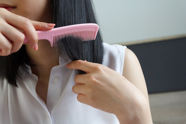 Chiuda in su della donna asiatica che pettina i capelli.