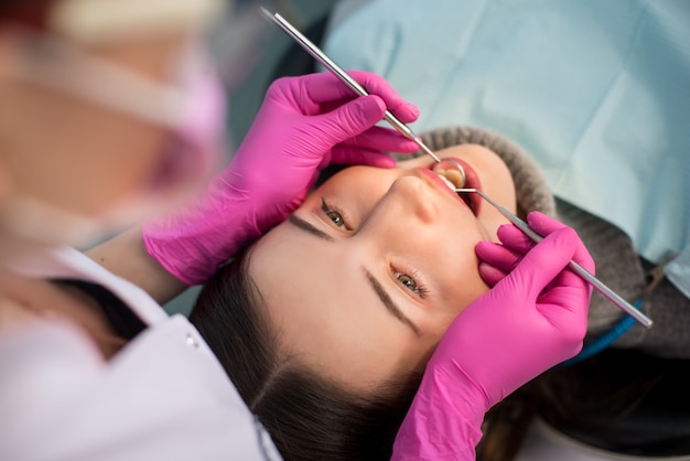 Chiuda in su della donna che ha controllo dentale in su in studio dentistico