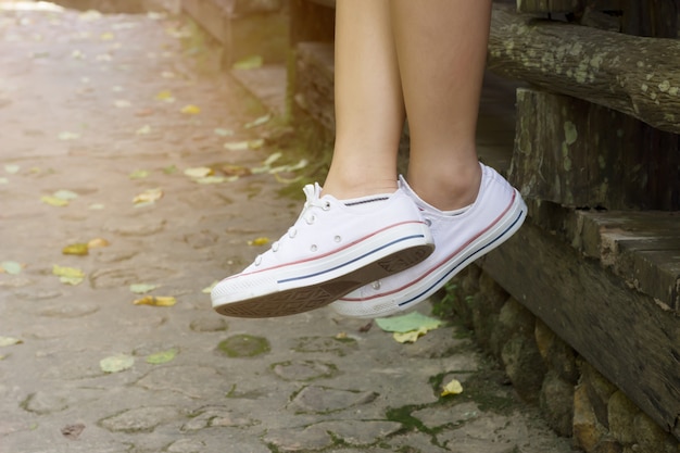 Chiuda in su della donna in scarpe da tennis bianche