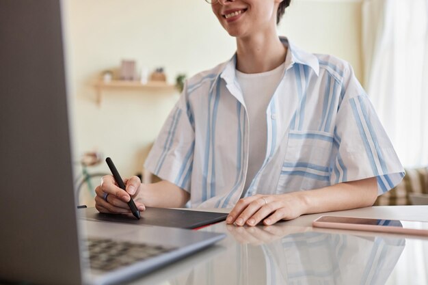 Chiuda in su della giovane donna sorridente che utilizza la pen tablet per la progettazione digitale a casa ufficio sul posto di lavoro copia sp