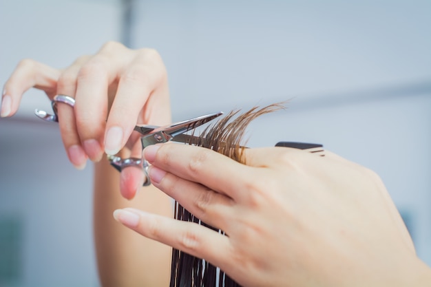 Chiuda in su della mano dell&#39;estetista con un taglio di capelli di donna