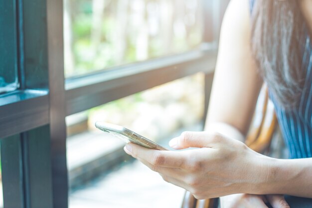 Chiuda in su della mano della donna usando un telefono cellulare