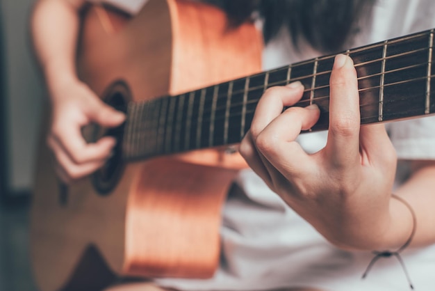 Chiuda in su della mano delle donne che suona la chitarra