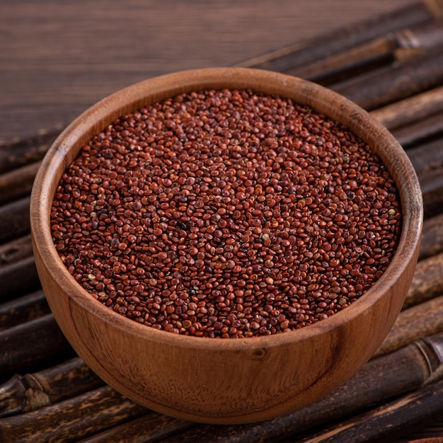 Chiuda in su della quinoa rossa organica in una ciotola sul fondo della tavola di legno