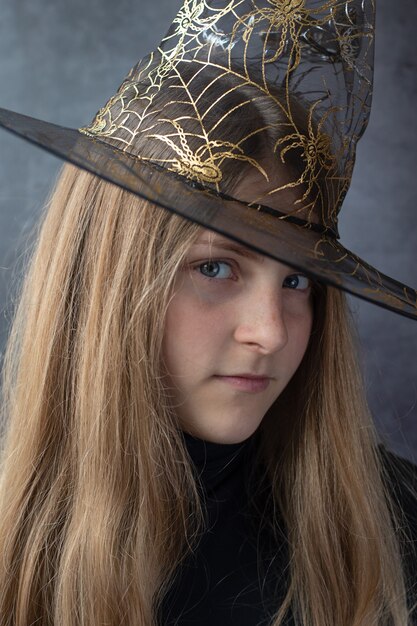 Chiuda in su della ragazza dell'adolescente in un cappello dei witcher di Halloween. Persone, Halloween, concetto di decorazione.