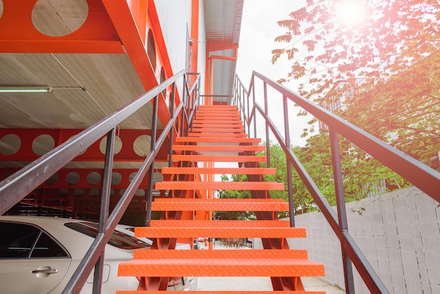 Chiuda in su della scala d'acciaio arancione o scala all'esterno dell'edificio.