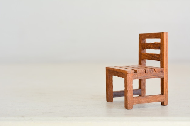 Chiuda in su della sedia miniatura del giocattolo sulla tabella di legno.