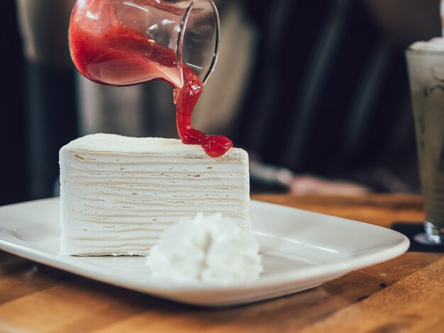 Chiuda in su della torta di crepe con salsa alla fragola.