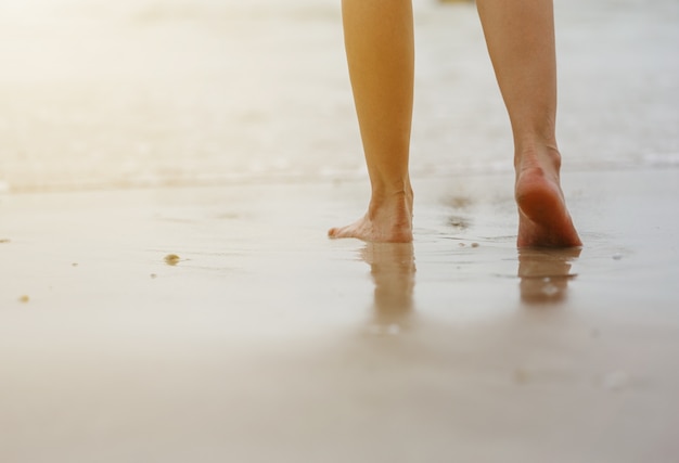 Chiuda in su delle gambe femminili che camminano sulla spiaggia